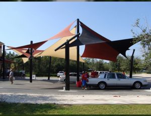 Tan, black, and red commercial sun shade panels for a parking lot