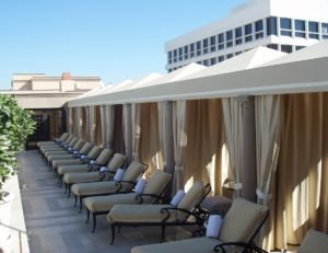 Commercial cabanas with tan awning fabric and drapes