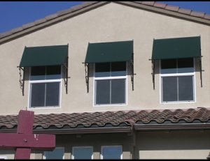 Green awning fabric on residential window awnings