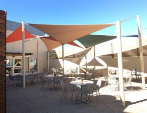 Tan, orange, and green commercial sun shade panels for an outdoor patio