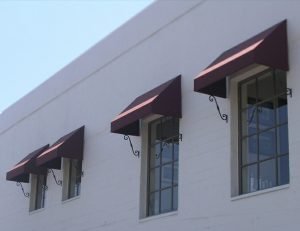 Residential window awnings with dark red awning fabric
